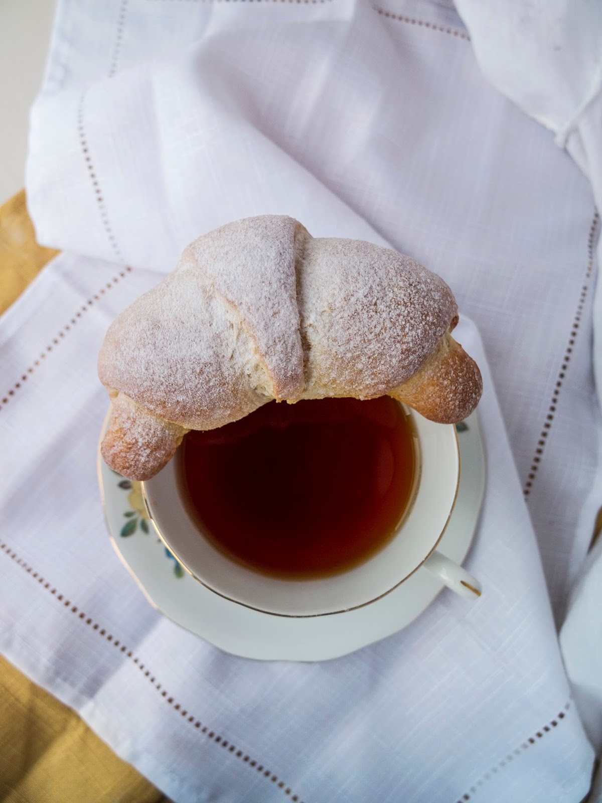 Baked yeast dough filled with chocolate sitting on a teacup.