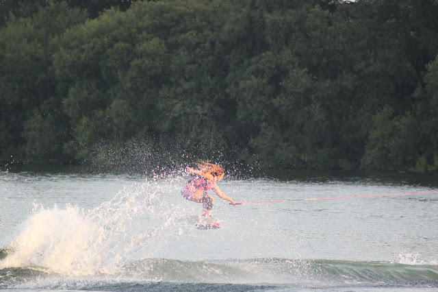 Women wakeboards across the lake, ready for a jump