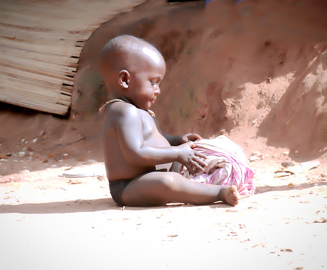 Precioso bebé africano jugando con objetos en un entorno hostil.