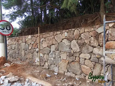 Construção do muro de pedra bruta sendo o tipo de pedra moledo com cores variadas sendo tipo de muro de pedra com junta seca sem massa nas juntas. Muro de pedra na cidade de Joanópolis-SP.