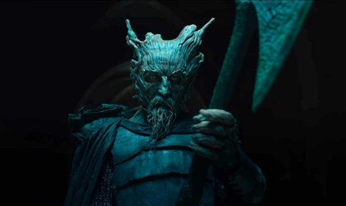 Imagem de capa: o Cavaleiro Verde, um humanóide com o rosto feito de madeira, uma barba e chifres feitos de madeira, usanso uma capa e segurando um machado.