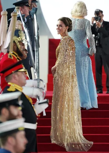 Kate Middleton wore a shimmering cape gown by Jenny Packham. Gold earrings. Aquazzura Fenix gold metallic leather pumps