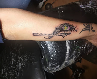 small peacock feather tattoo with flute