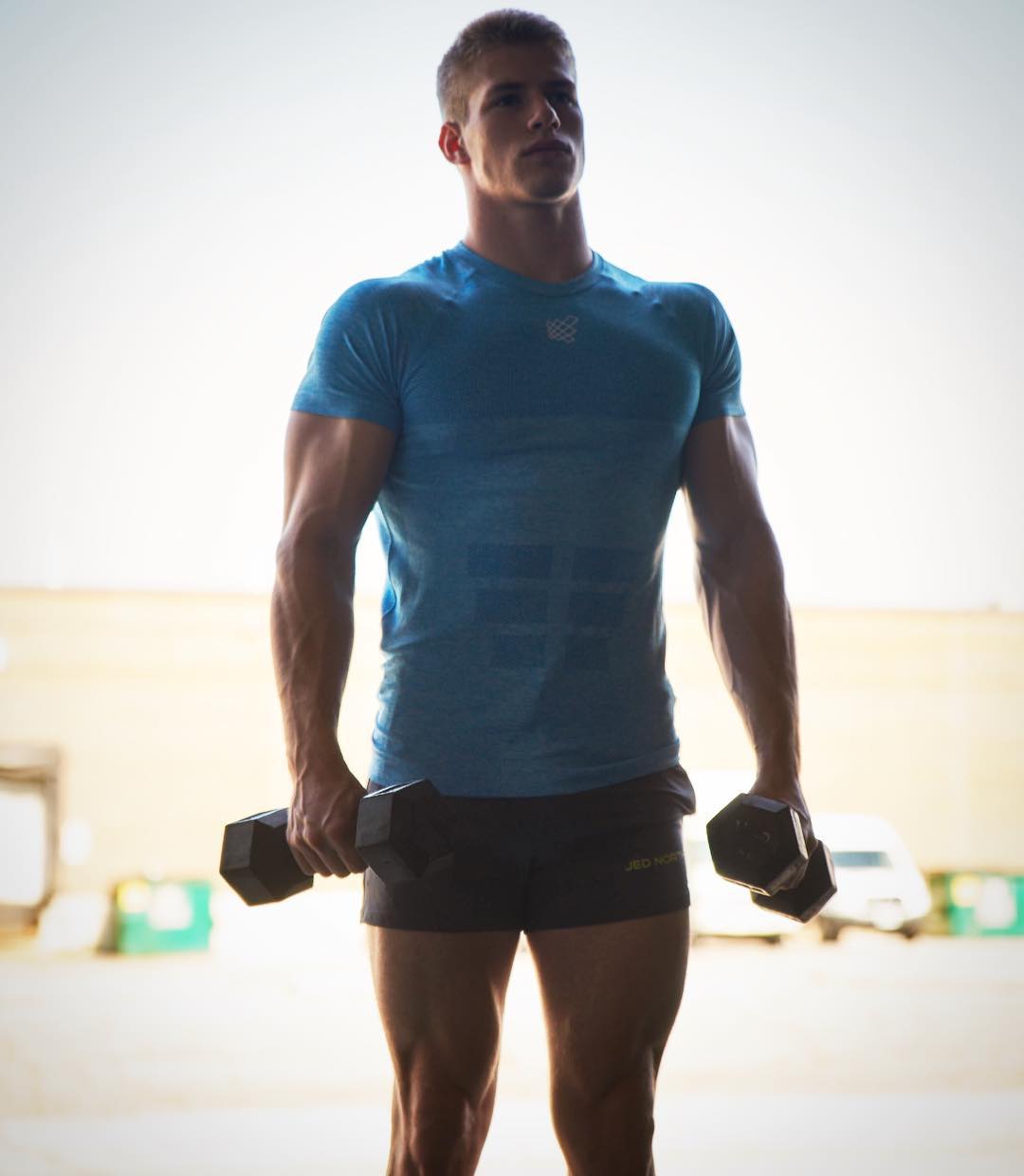 strong-young-hunk-lifting-dumbbells-blue-muscle-tshirt