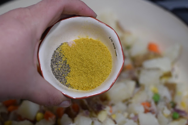 The spices being added to the pan with the vegetables.