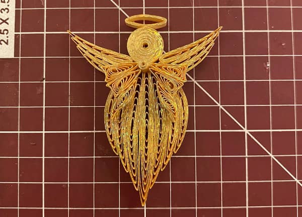 quilled angel in progress with body, head, wings, bow, and halo completed