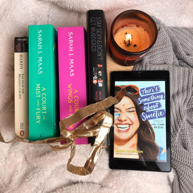 Top 10 books of 2020! Stack of books facing spine up next to a kindle showing the cover of 'There's Something About Sweetie' by Sandhya Menon