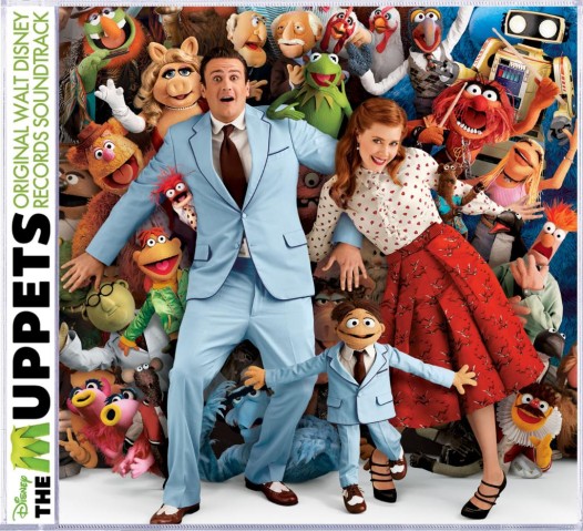 Jason Siegel, Amy Adams, and Walter in front of a veritable wall of familiar Muppets, including Kermit, Piggy, Fozzie, Animal, Gonzo, Beaker, and Scooter