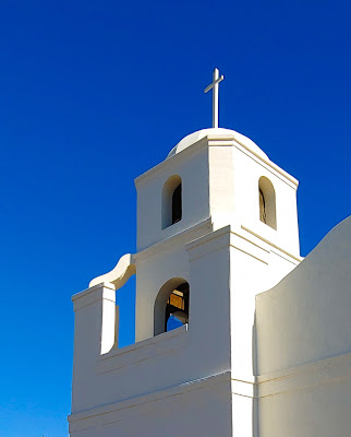 Bell tower of a white church with a white cross at the top