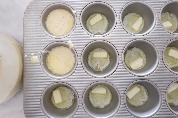 adding butter and batter to hot muffin tin