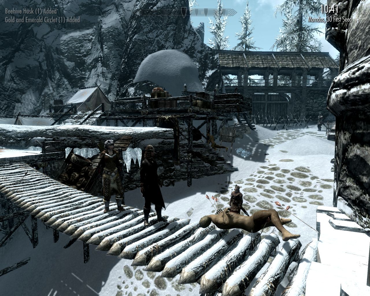 Laura and Lydia stand in front of a dead men with many arrows in his body