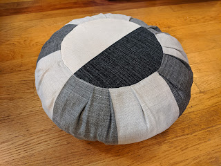 Slanted view of stuffed dark gray and off-white round meditation cushion