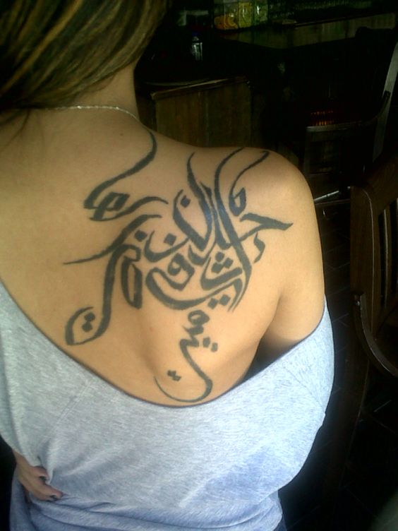 chica de espldas, lleva un tatuaje arabe en el omóplato