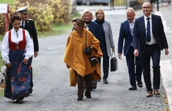 King Harald of Norway was hospitalized. Queen Sonja wore a pussy-bow floral-print stretch-crepe blouse, and yellow vest, and brown trousers