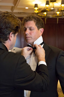 Steve gets into his tux. A friend helps his with his tie.