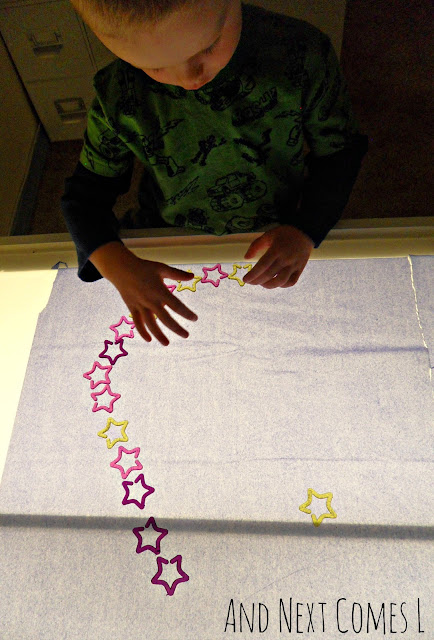 Child doing a constellation activity on the light table with translucent stars