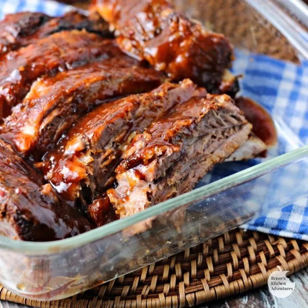 Fall-Off-The-Bone Slow Cooker Ribs by Renee's Kitchen Adventures cut into serving sizes in a clear dish ready to serve