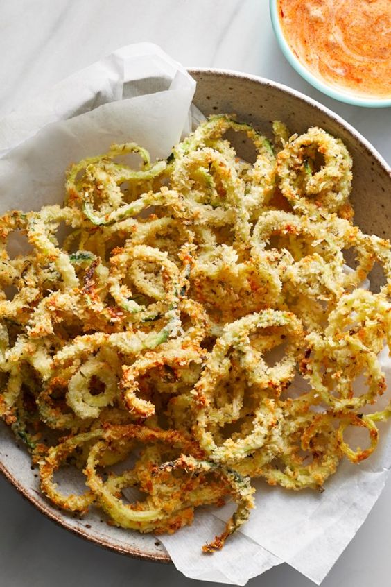 This healthy recipe combines two bar food favorites—fried zucchini and curly fries—into one tempting package. Serve these baked zucchini fries with a simple dipping sauce made with ranch dressing and marinara sauce for a crowd-pleasing appetizer or a side dish for burgers, chicken or pizza. #comfortfood #comfortfoodrecipes #healthycomfortfood #healthycomfortfoodrecipes #recipe #eatingwell #healthy