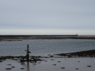 Berwick Pier and Lighthouse as seen from Spittal with a rotting wooden structure in the mud of low tide at the forefront of the photo.  Photo by Kevin Nosferatu for the Skulferatu Project.