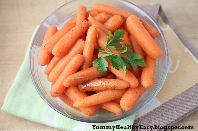 Big bowl of cooked carrots with a sprig of parsley on top.