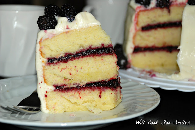 slice of blackberry cake on a plate with blackberries on top