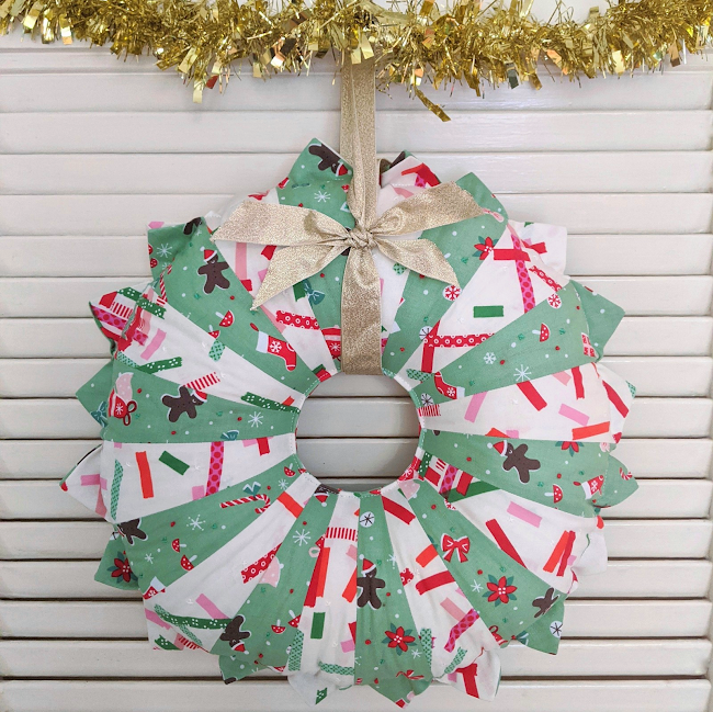 fabric christmas wreath made of patchwork dresden plates hanging up with tinsel