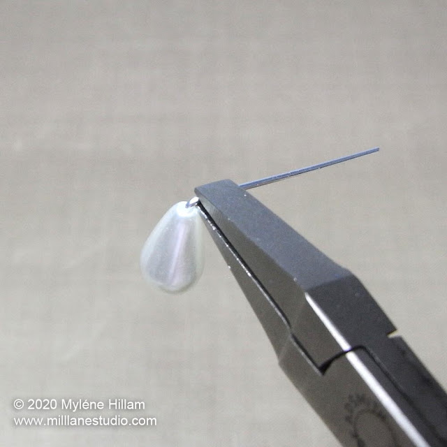 Bending a head pin at a 90° angle above a pearl teardrop using flat nose pliers