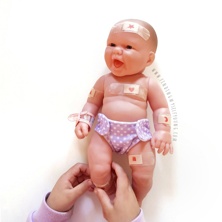 Child putting baindaids onto a plastic baby doll