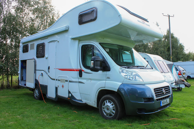 Side view of a large motorhome with a big back door wide open.