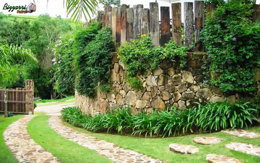 Caminhos de pedra moledo ao lado do muro de pedra com a execução do paisagismo.