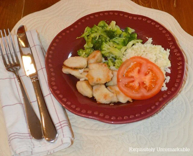 Chicken nuggets, rice, tomatoes and broccoli on red plate