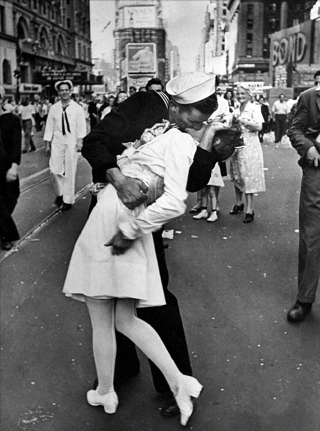 AMERICAN SAILOR CLUTCHING A WHITE-UNIFORMED NURSE IN A PASSIONATE KISS IN TIMES SQUARE