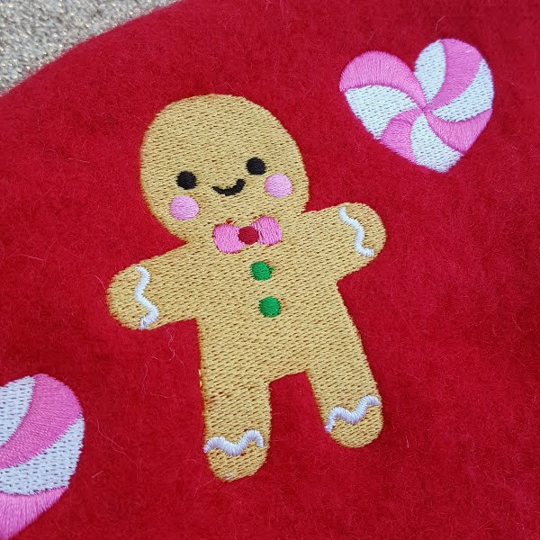 close up of embroidered gingerbread man on red wool beret