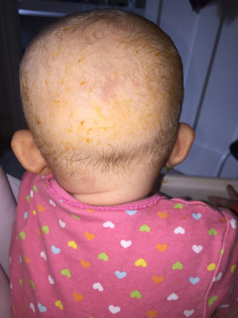 Messy back of head The back of a baby's head with hardly any hair with orange food mess smeared