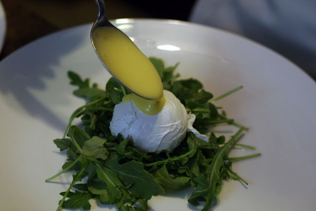Adding homemade hollandaise sauce to the finished poached egg.