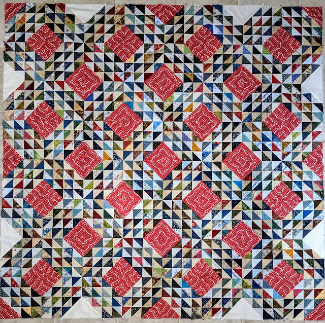 Tethys Waves, an Ocean Waves quilt top Small HSTS in blues, reds, greens, golds, and creams surround the large red and white print squares