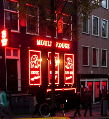 Mujer vistiendo blusa negra, mini falda gris, pantimedias y tacones altos negros