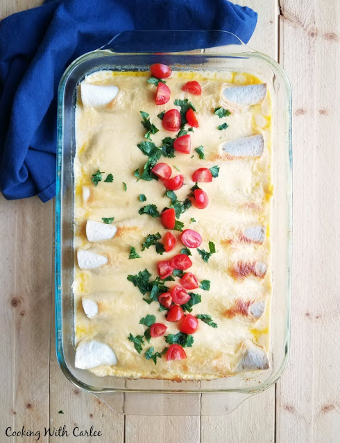 The perfect use for leftover pulled pork! These pulled pork enchiladas are part BBQ and part enchilada. They are creamy, cheesy and oh so good! pan of creamy cheesy enchiladas topped with chopped tomatoes and cilantro, ready to serve