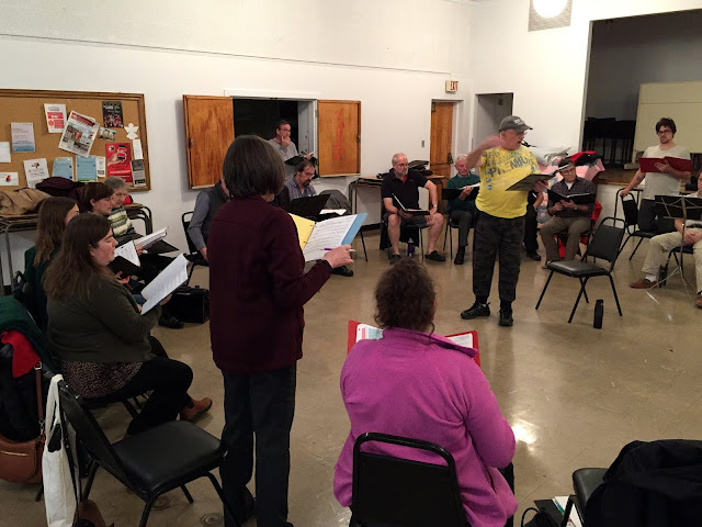 Director Pierre runs choir rehearsal from the middle of the circle of singers 