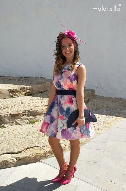 Invitada a boda perfecta con vestido estampado corto, bolso abanico azul navy, zapatos tacón lace up fucsia y tocado tipo casquete con orquideas