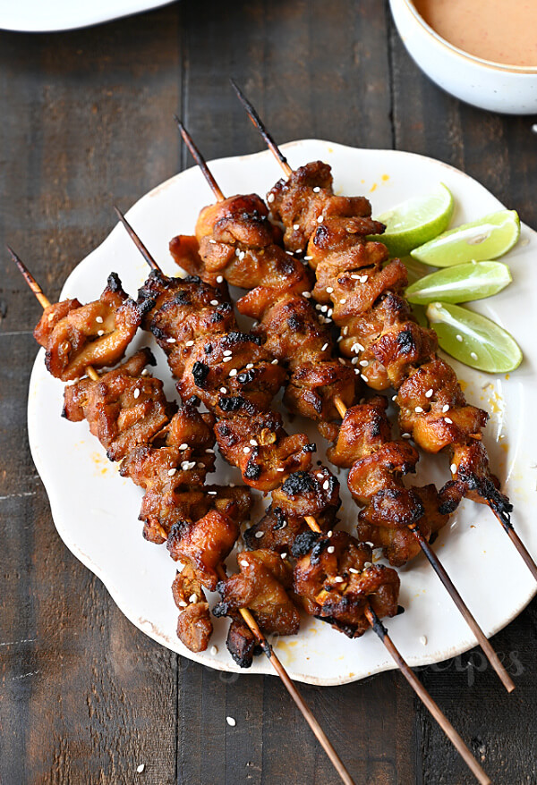 a white plate with Thai coconut grilled chicken skewers