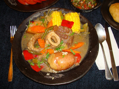 This typical Chilean recipe is probably originated from France. It is a boiled dinner made with meat and vegetables that in France is called Pot Au Feu. It is a comfort food especially great in winter time, but in Chile is better made in summer time because of the fresh vegetables that are used in the elaboration of this the dish. Fresh string beans, fresh corn, butternut squash or calabaza (zapallo), peppers, fresh herbs, etc. This food is typically served in hot clay dishes that will maintain the food hot for the duration of the dinner. Usually served with a tomato salad and onions, fresh made bread (pan batido) and of course it is indispensable to serve “pebre”, that is  a cold sauce made of tomatoes, hot pepper, cilantro, garlic, onions, vinegar and oil. This sauce could be drizzle on the soup or eat it with fresh bread. (pebre sopeado con pan).  The recipe that follows is for 2 people, but you’ll have soup left over for dinner.  PORTIONS: 2 INGREDIENTS 2 pieces of beef shank with bone in center   ½ tbsp. flour 1½ tbsp. vegetable oil 8 cups (2 qt.) water 2 cubes beef bouillon ¼ tsp. oregano ¼ tsp. thyme leaves 1 bay leaf 1 tsp. salt ½ tsp. ground black pepper 1 medium diced onion 2 sliced garlic cloves 2 large carrots sliced 1 celery rib sliced ½ red bell pepper cut in big squares 1 cup white wine (Rhine) 1 cup string beans cut in pieces 2 butternut squash shanks  2 corn on the cob cut in half. 2 red potatoes washed with skin on. I like it with skin. You may peel it if you want too. ¼ cup long grain brown rice ¾ cups water 1 tbsp. chopped cilantro METHOD Measure and cut all ingredients necessary for the recipe. In a small pot cook the brown rice with ¾ cup water for about 40 minutes until soft. Dust the beef shanks with the flour. Heat up a frying pan with the vegetable oil and at moderate heat brown the beef on both sides. Turn off heat. In a large pot place the beef. Pour in the 2 quarts of water. Add beef bouillon, oregano, thyme leaves, bay leaf, salt and black pepper. At moderate heat bring the liquid to a boil. Lower the flame and let simmer for about 30 minutes, until beef is seamy soft. Same frying pan heat up again and mix in onions, garlic, carrots and celery. Keep cooking until onions start browning. Deglaze the pan with the wine. Incorporate the vegetables and liquid to the beef. Add to the pot, string beans, butternut squash shanks, corn on the cob and potatoes. Let cook the beef with all the vegetables at a moderate heat for approximately 30 more minutes until potatoes are soft but not falling apart. Heat the clay soup bowl dishes and serve the soup  Serve small dishes with “pebre sauce” and fresh bread. PORTIONS: 2 INGREDIENTS 2 pieces of beef shank with bone in center   ½ tbsp. flour 1½ tbsp. vegetable oil 8 cups (2 qt.) water 2 cubes beef bouillon ¼ tsp. oregano ¼ tsp. thyme leaves 1 bay leaf 1 tsp. salt ½ tsp. ground black pepper 1 medium diced onion 2 sliced garlic cloves 2 large carrots sliced 1 celery rib sliced ½ red bell pepper cut in big squares 1 cup white wine (Rhine) 1 cup string beans cut in pieces 2 butternut squash shanks  2 corn on the cob cut in half. 2 red potatoes washed with skin on. I like it with skin. You may peel it if you want too. ¼ cup long grain brown rice ¾ cups water 1 tbsp. chopped cilantro METHOD Measure and cut all ingredients necessary for the recipe. In a small pot cook the brown rice with ¾ cup water for about 40 minutes until soft. Dust the beef shanks with the flour. Heat up a frying pan with the vegetable oil and at moderate heat brown the beef on both sides. Turn off heat. In a large pot place the beef. Pour in the 2 quarts of water. Add beef bouillon, oregano, thyme leaves, bay leaf, salt and black pepper. At moderate heat bring the liquid to a boil. Lower the flame and let simmer for about 30 minutes, until beef is soft. Same frying pan heat up again and mix in onions, garlic, carrots, red peppers and celery. Keep cooking until onions start browning.  Deglaze the pan with the wine.  Incorporate the vegetables and liquid to the beef. Add to the pot, string beans, butternut squash shanks, corn on the cob and potatoes. Let cook the beef with all the vegetables at a moderate heat for approximately 30 more minutes until potatoes are soft but not falling apart. Heat the clay soup bowl dishes and serve the soup  Serve small dishes with “pebre sauce” and fresh bread. Ingredients for pebre Pebre CEDE: 1¼ tazas INGREDIENTES 3/4 taza de cebolla picada en cuadritos. 2 cucharas de ají cacho de cabra fresco, picado con semillas. 1/3 taza de cebollinos verdes cortados a lo ancho bien delgadito. 2 dientes de ajo picados bien fino. ½ taza de tomates cortados en cuadritos. 1/4 taza de aceite de oliva. 1 cuchara de vinagre. 1/4 taza de cilantro lavado, picado. 3/4 de cucharita de sal. PREPARACIÓN En un recipiente mezclar todos los ingredientes y servir con sus comidas, que nunca falte en la mesa. Nota: Si no le gusta el ajo mala cueva. OPCIONAL:  Hay veces que prefiero hacer el pebre sin  el vinagre, por lo general es cuando lo quiero poner en una sopa. No le pongo el vinagre para que no me amargue la sopa y solo tenga el sabor de los otros condimentos del pebre. Tomato salad with red onions Marraqueta bread PAN BATIDO, MARRAQUETA This is a very popular bread in Chile. We are lucky that in Chile we have so many bakeries we can buy just fresh made bread. You may go different hours and you can find bread just coming out of the ovens. Sometimes I think I should carry a stick of butter and use it at the moment I am buying the bread, because it is so hot, the butter will melt right away. You need to use a paper bag, because if you use plastic, the bread will sweat. There are a lot of varieties so it’s tough to choose sometimes. PORCIONES: 7 MARRAQUETAS INGREDIENTES 45 oz. (1270 g.) Bread flour 2 tbsp. instant dry yeast 1 tbsp. salt 1½ tsp. sugar 3½ cups warm water, 110° F METHOD In a stand up machine mixer bowl put in flour, dry yeast, salt, sugar and warm water.  Mix in the bowl for about 8 minutes. The dough should come off loose from the bowl sides. Cover the bowl with a plastic and let it ferment for about 1 hour or until doubles in size. All depends on the room temperature. After it doubles in size, push in the dough and turn it around. Let it double in size again. Make 14 smooth balls with the dough. Oil a baking sheet pan. Put 2 balls together and using a long stick push in the center of the dough length wise dividing the dough.  Do this step with all the dough balls. Brush the top of the bread with oil. Preheat the oven at 425° F  Place a metal container with water at the bottom of the stove to keep moisture inside the oven while baking the bread. Or you can spray some water on top while cooking. Cook the bread until golden brown.