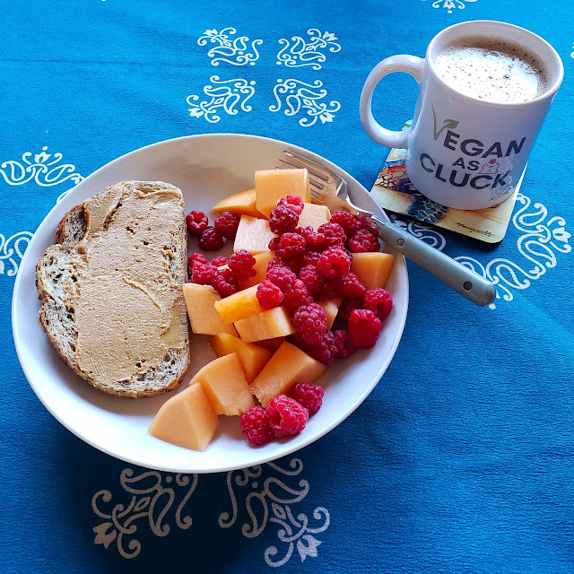 Toast and peanut butter with cantaloupe and raspberries, and a cup of coffee