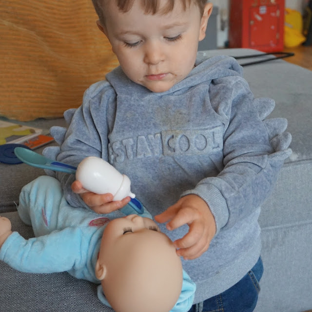 image shows a young boy playing with a baby doll. 