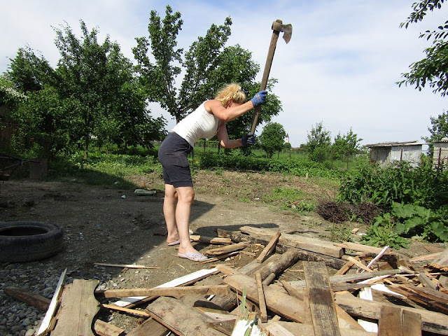 blonde woman cutting wood with an axe