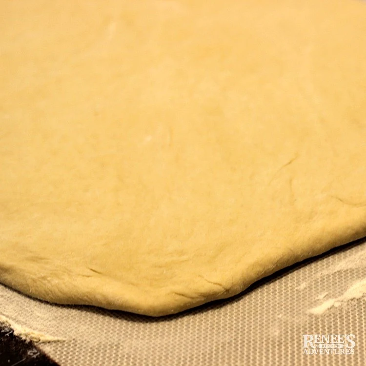 Process shot of dough rolled out into a rectangle for Apple Cinnamon Rolls with Maple Frosting by Renee's Kitchen Adventures