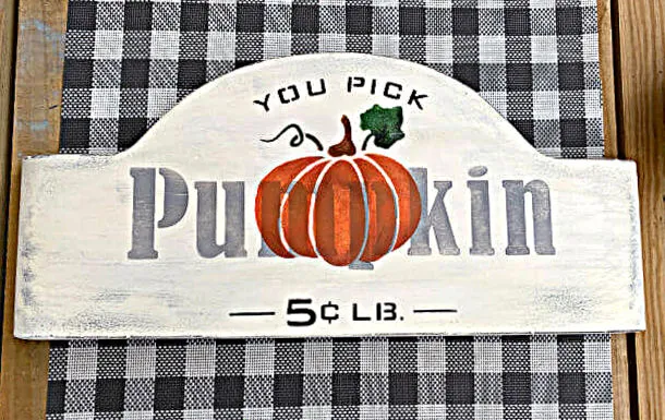 stenciled pumpkin sign with a buffalo check background