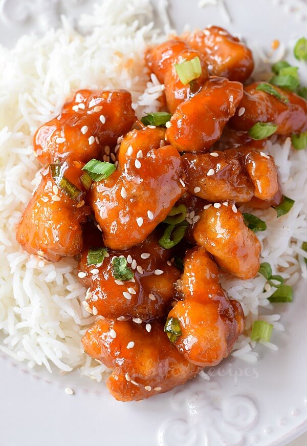 top view of a white plate with rice served along with sweet and sour chicken