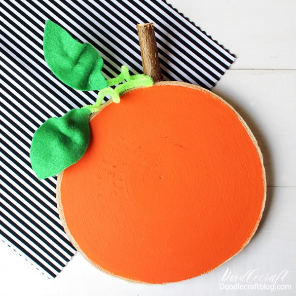 Pumpkins are the perfect symbol of Autumn. This rustic wood slice pumpkin is the perfect Fall craft DIY and just takes 5 minutes to complete!   This cute pumpkin can sit on the mantle with Autumn decor. Attach it to a wreath for the perfect front door decor. If you want to make it perfect for Halloween, get some black paint and give it a Jack-o-lantern face.