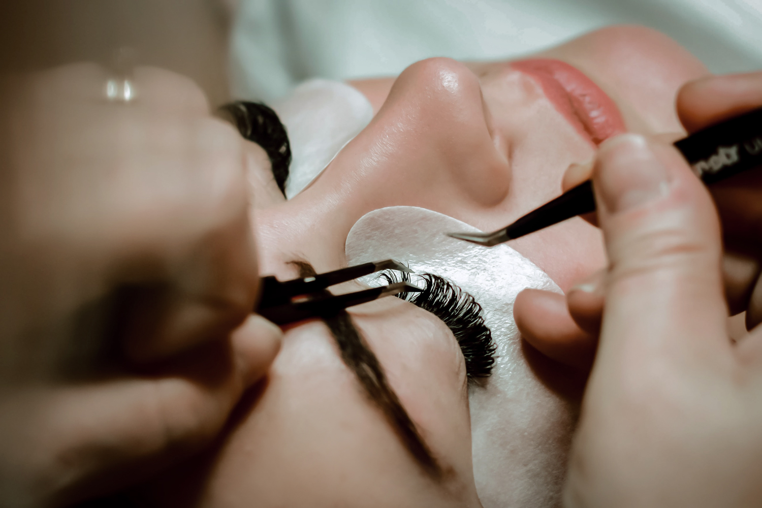 a close up of a person applying eyelash extensions on an eye